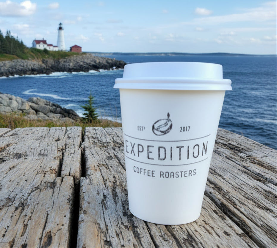 Expedition Coffee Roasters cup on a wooden table with a coffee shop interior in the background
